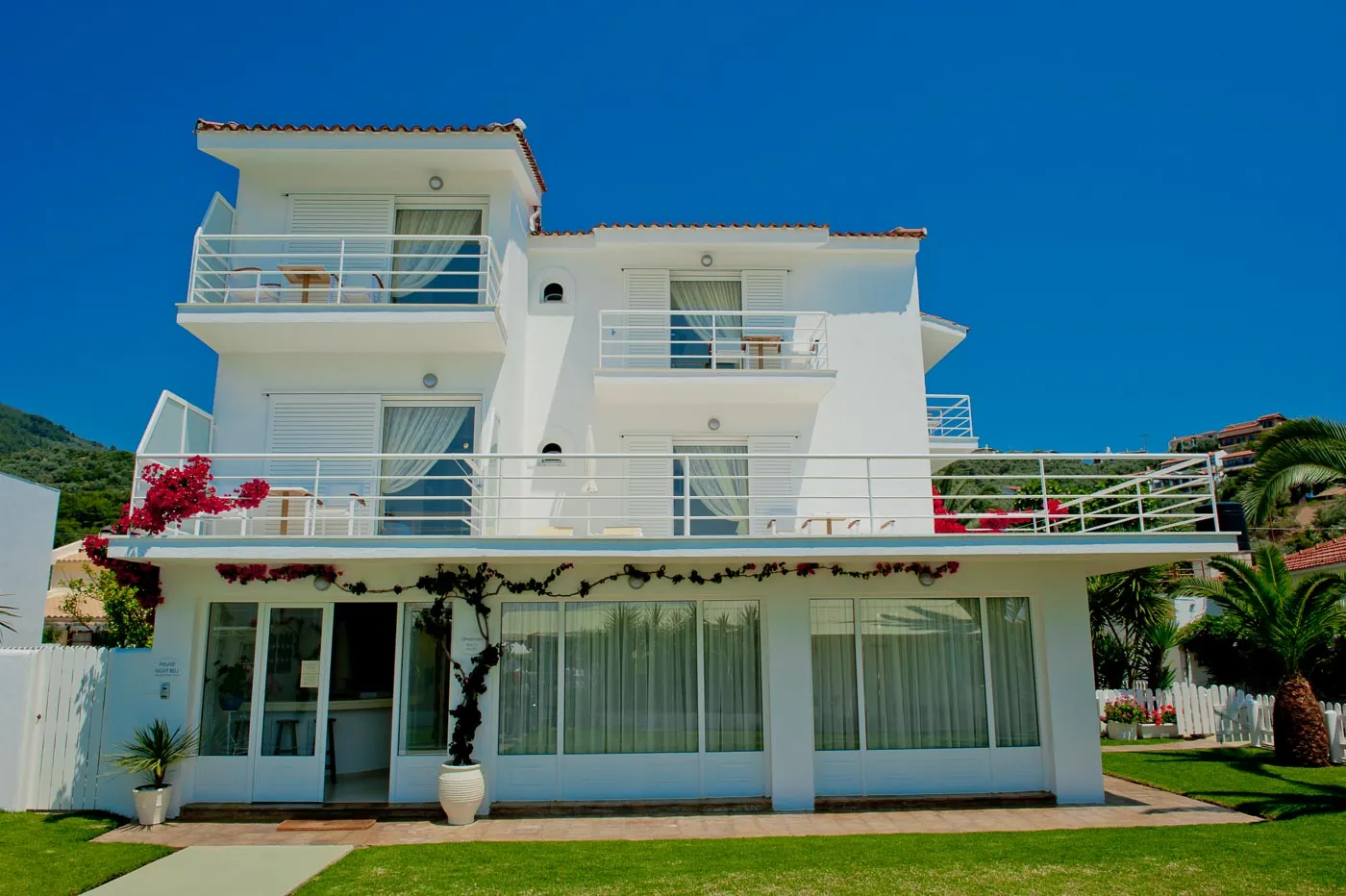 The hotel: white balconies, bougainvillea and a green lawn