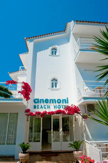 The entrance with the Anemoni Beach Hotel sign and bougainvillea