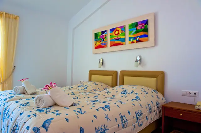 Twin beds with sea-print covers beneath a colourful painting
